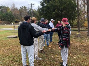 Students gathered doing a low ropes course activity outside