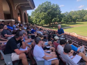 President Stimpert talking with students in the football stadium stands